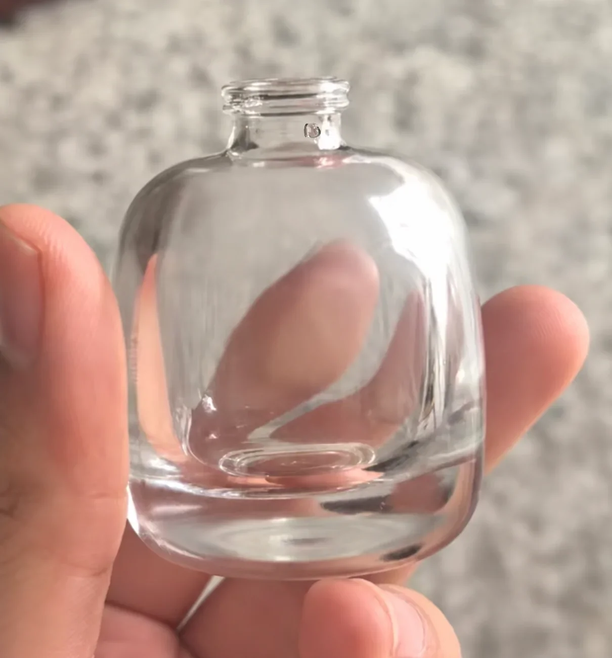 Clear round perfume bottle illustrating a neck defect